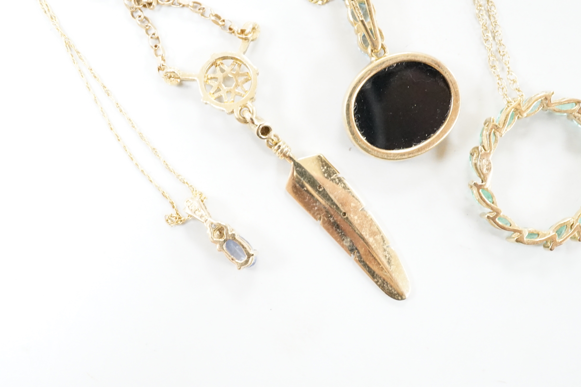 Three assorted modern 9ct or yellow metal and gem set pendants, on 9ct chains including opal doublet and blue topaz, feather shape and emerald set circular and a similar 10k pendant, on a 10k chain, longest 52cm, gross w